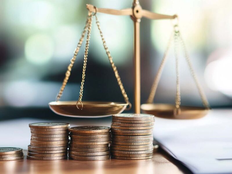 A conceptual shot of scales balancing coins and tax documents, symbolizing financial justice and accountability. image conveys importance of balance in financial matters