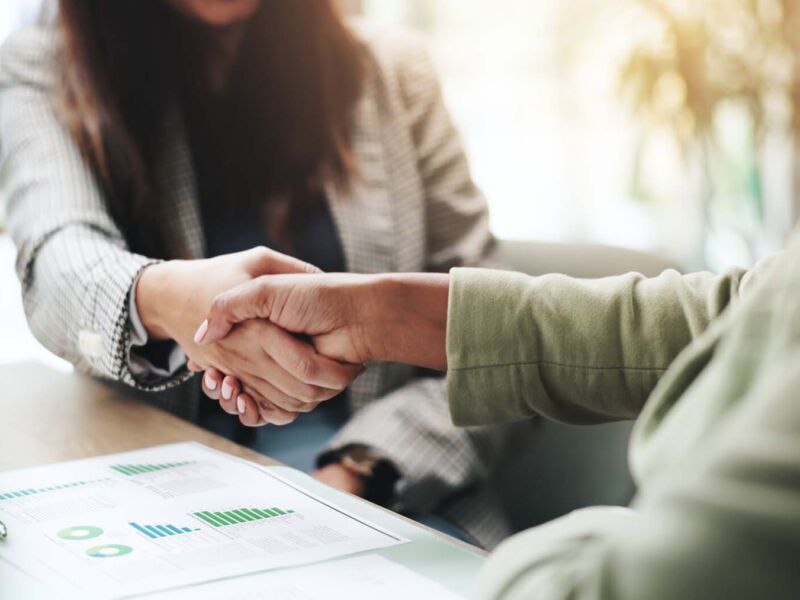 Hands, business people and handshake with deal, graphs and profit growth or sales analytics. Closeup, thank you and financial advisor with agreement, B2B welcome or CRM with charts or company revenue.